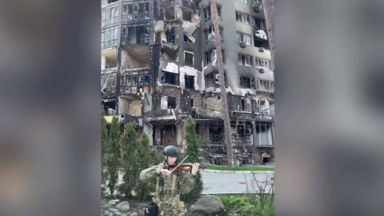 Ucraina, un soldato suona il violino davanti ai palazzi distrutti a Irpin