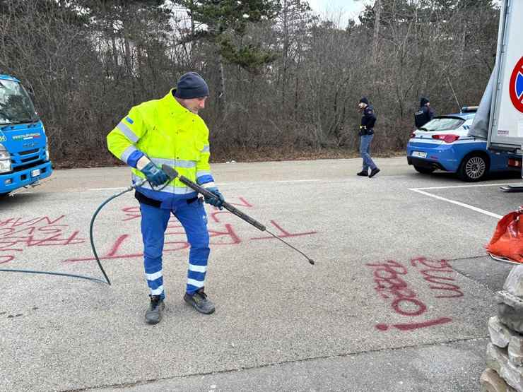 Operai ripuliscono la foiba imbrattata con scritte offensive nella notte a Basovizza